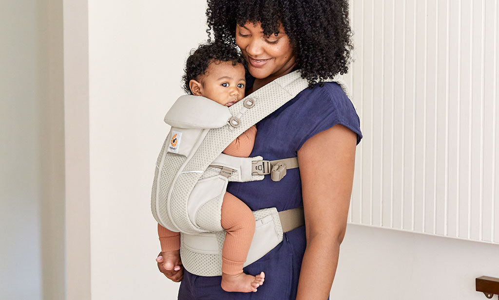 une maman qui porte son bébé avec un porte-bébé évolutif