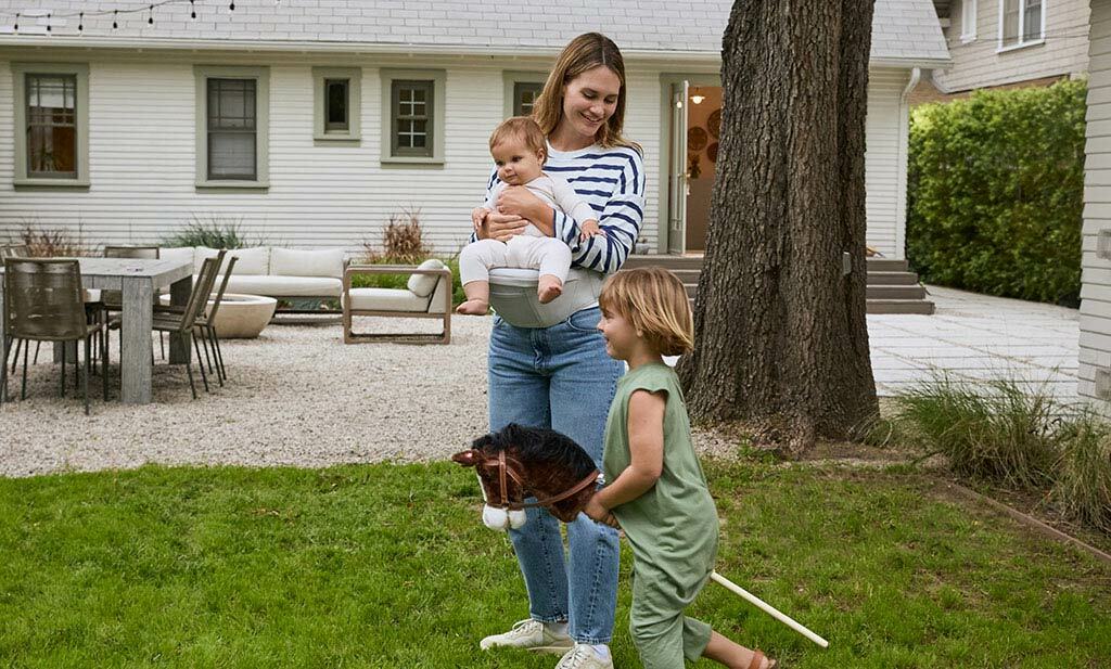 Maman jouant avec ses enfants et portant son bébé avec Lift Hip Seat